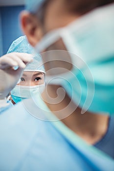 Close-up of nurse helping a surgeon in tying surgical mask