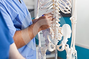 Close up of nurse pointing at spine bones on human skeleton