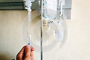 Close-up of a nurse`s hand adjusting the physiological serum dropper in a hospital