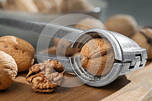 Close-up of a nutcracker and raw walnuts on a wooden board. From a low angle view indoors