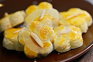 Close-up of Nyonya almond cookies, on a dark brown saucer