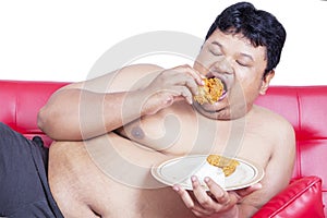 Close up of an obesity man eating chicken on studio