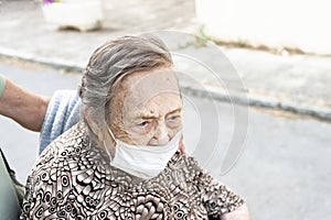 close-up of an octogenarian woman walking down the street in a wheelchair