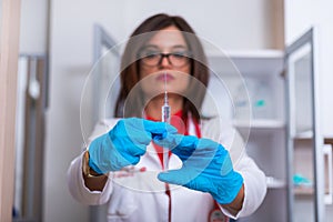 Close up of a female doctor  nurse  holding a syringe while standing in a medical office