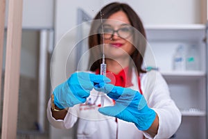 Close up od a female doctor  nurse  holding a syringe while standing in a medical office