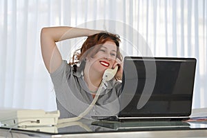 Woman sitting at her desk working and answering a phone call