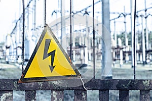 Close-up old aged rusty triangle metal plate with High voltage warning sign. Power station with transformers and