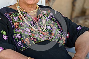 Close up of old Arab woman with traditional arabian dress sitting on chair.