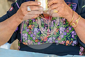 Close up of old arabian woman hands with traditional arabian dress and jewelry holding cup of coffee.