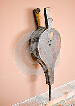 close up of an old bellows made in leather and wood. The bellows in vertical position is rested on a wall of bricks and an a brown