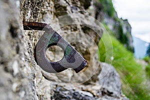 Close up of old bent piton used for mountaineering, fixed into a crack on a rock wall, part of an old climbing route, in mountains