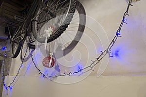 Close-up old bicycle hanging on the wall with Christmas lights