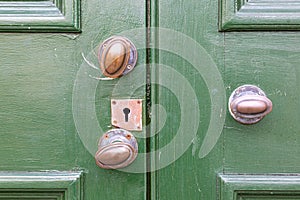 A close up of old brass door knobs on a green wooden door