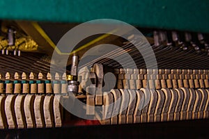 Close up of old broken dusty piano from the inside. Hammers in abandoned piano striking strings. Music playing from the ancient