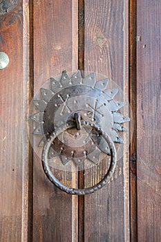 Close-up of old brown wooden massive gate, closed door, handmade iron handles and knockers