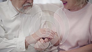 Close-up of old Caucasian elegant man kissing wife`s hand. Senior couple in love spending time together. Happy retirees
