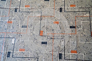 Close up of old, cracked and peeling linoleum with a gray, orange and black square design photo