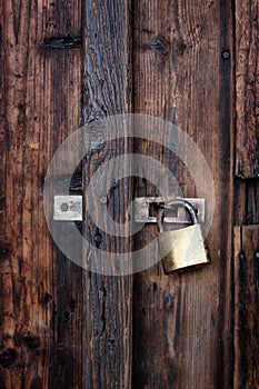 Old dark brown wooden door with padlock.