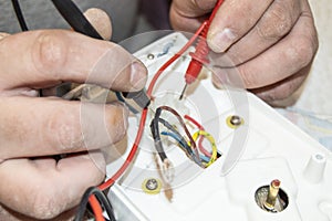 Close-up of the old electrician`s hand, the use of digital voltmeter for voltage to repair the electric iron, selective