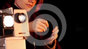Close-up of an old fashioned slide projector and a young woman inserting its supplements