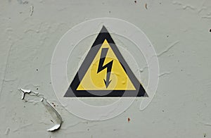 Close up of old Grey Hinged Power Supply Box with yellow danger warning sign electricity in remote places