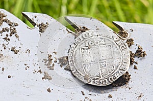 Close- up on old, hammered silver coin exposed on a shovel ,found in life dig by metal detector.