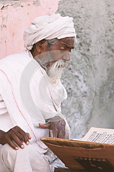 Close up of an old indian sadhu reading scriptures.