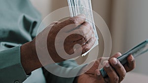 Close-up old male African American hands counting money dollars indoors. Unrecognizable senior mature man calculating