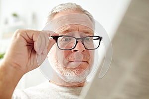 Close up of old man in glasses reading newspaper