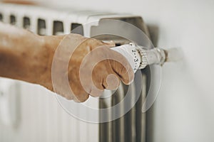 Close up of old man hand closing  heating home thermostat for gas energy saving. Concept of bills and heat crisis costs. People photo