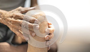 Close up of old man hand holding on the knee with suffering from knee pain. The sick legs of an old man with severely deformed