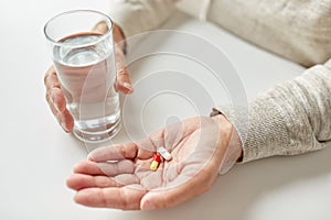 Close up of old man hands with pills and water