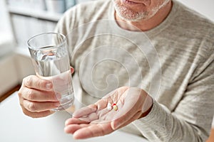 Close up of old man hands with pills and water