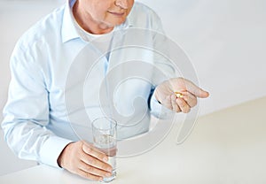 Close up of old man with pills and water glass