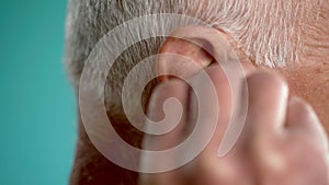 Close-up of an old man putting headphones into his ear