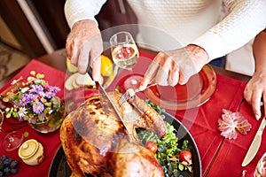 Close-up old man serving roasted turkey on a table background. Thanksgiving dinner. Traditional festive food concept.