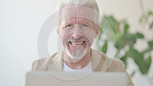 Close Up of Old Man Smiling at Camera while using Laptop in Office