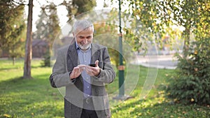Close up of old man with white beard using smartphone outside