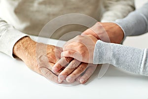 Close up of old man and young woman holding hands