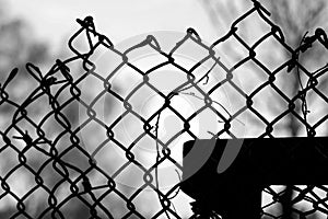 Close-up of an old metal mesh fence against sky black and white