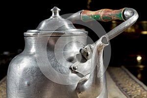 Close-up of old metallic teapot with wooden handle