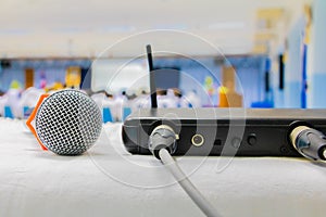 Close up old microphone wireless with box signal on the white table in business conference interior seminar meeting room