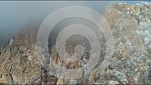 Close-up of old mountain peaks in clouds covered by frozen small trees and shrubs. Shot. Amazing mountain view.