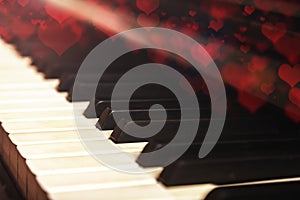Close-up of old piano keyboard, selective focus, soft toning. Valentine`s day background, vintage piano and bokeh hearts