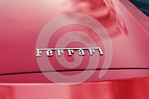 Close-up of an old red car with the name "Ferrari" visible on the hood