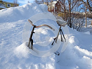Close-up of old rusty bicycle buried in thick layer of snow in Finnish Lapland. Snowy landscape and extreme nature