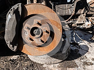 A close-up on the old rusty brake system of a car with pads, discs, a caliper on a lift in a vehicle repair workshop. Auto service