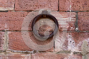 Close up of old rusty iron ring on a red brick wall