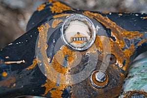 Close-up of an old rusty steering wheel of a two-wheeled motorcycle with a broken speedometer.