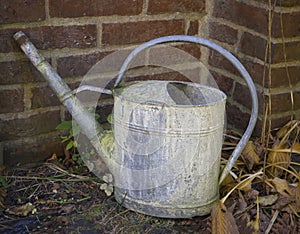 Close up old rusty tin watering can in cemetery wall